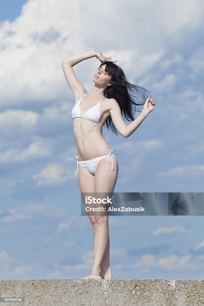 Atrakcyjna młoda kobieta w bieli na tle zachmurzenie nieba - Zbiór zdjęć royalty-free (20-24 lata)