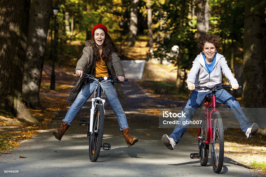 Urban biking- girl and boy riding bikes in city park Active young people riding bikes  Cycling Stock Photo