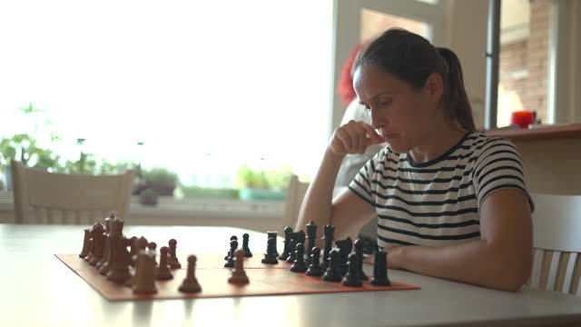 Mature woman playing chess with her girlfriend.