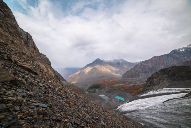 Awesome top view to turquoise eyes-lakes and pyramid shaped high mountain. Three beautiful mountain lakes among fading autumn colors. Small glacial lakes and sharp peak. Sunlight and shadows of clouds