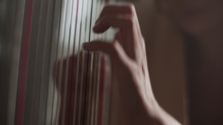 Hands of female harpist plucking strings of harp