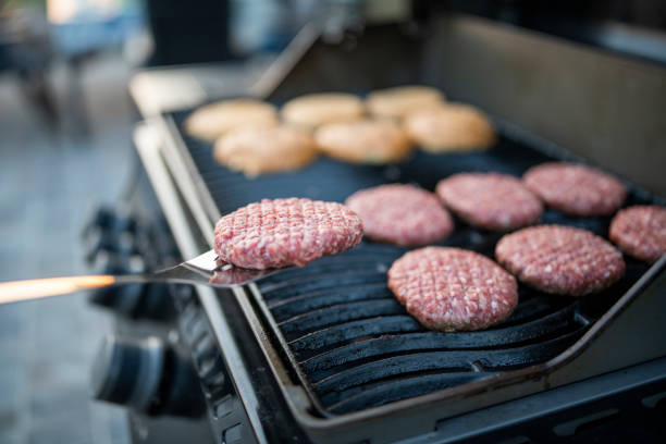 Mid adult man preparing burgers on grill at a garden party.