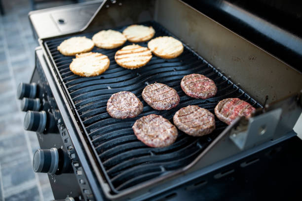 Preparation of delicious fresh homemade beef burgers on a barbeque in the backyard.