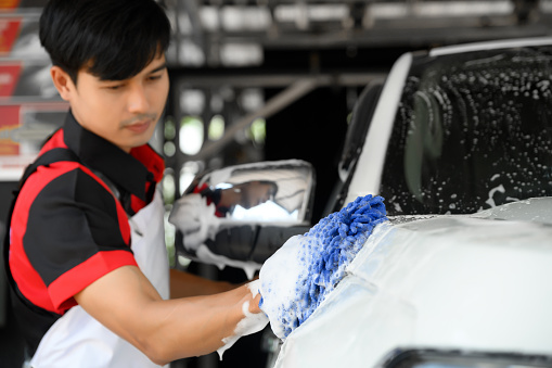 Man Worker use Soap Washing and Taking Care of Vehicle car body with Diligence, Car Washing and Detailing to Shiny and Clean Vehicles for Automotive Maintenance.