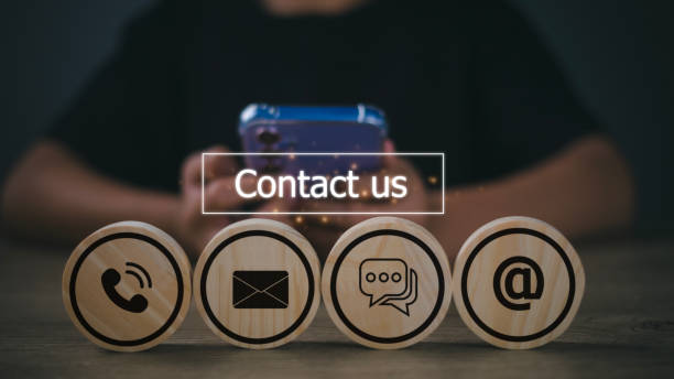 istock Contact Us concept with icons on wooden blocks. Man is using a smartphone. customer support concept 1675007185