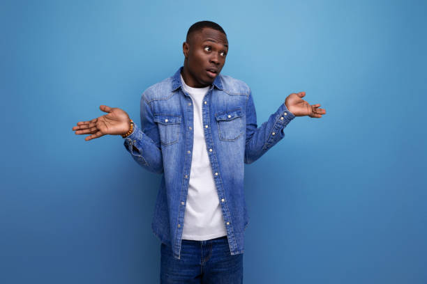 istock handsome young american man in denim jacket shrugging on blue background with copy space 1675031947
