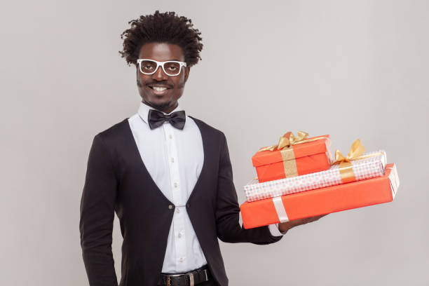 istock Joyful cheerful man in glasses standing holding three present boxes, being in festive mood. 1675139414