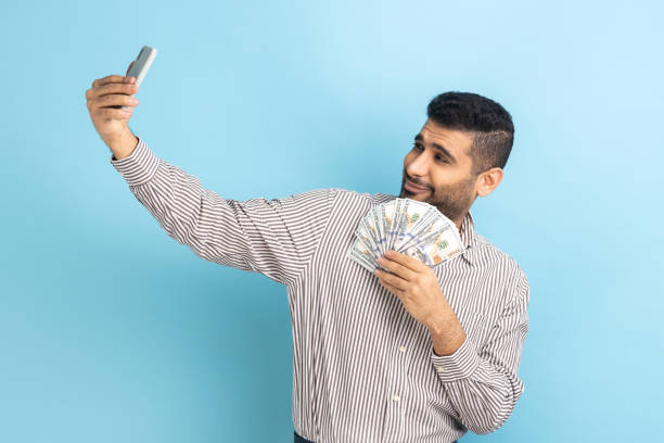 geschäftsmann, der selfie-foto mit einem haufen dollar auf dem smartphone macht und mit reichtum prahlt. - angeberei stock-fotos und bilder