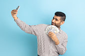 Businessman making selfie photo with bunch of dollars on smartphone, bragging with wealth.