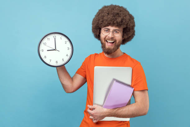 istock Man holding paper notebook and laptop, showing big wall clock, finish work in time. 1675157269