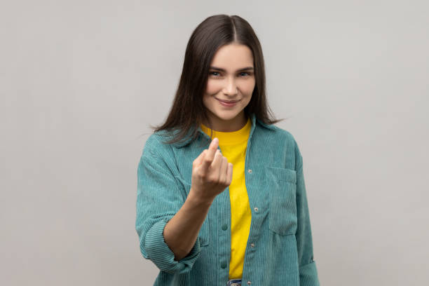 Attractive woman gesturing come to me, beckoning with finger, inviting for confidential talk. stock photo