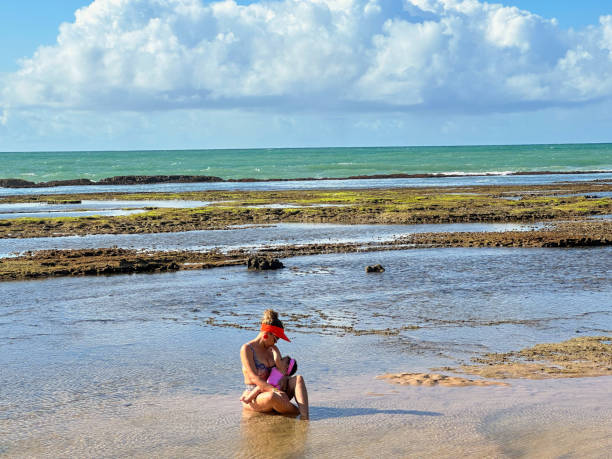 Mother breastfeeding daughter in natural pools