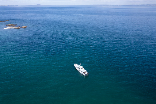 An idyllic scene of a large motorboat moored in the turquoise waters of the Hauraki Gulf, Auckland, NZ