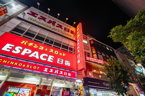 Espace Pachinko & Slot in Tokyo, Japan. A gambiling establishment taken at night from the outside. The sign is red and has lots of neon lights
