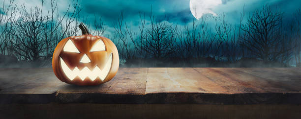 istock Jack O 'Lanterns with glowing eyes on a wooden table on spooky Halloween night under full moon light 1675219657