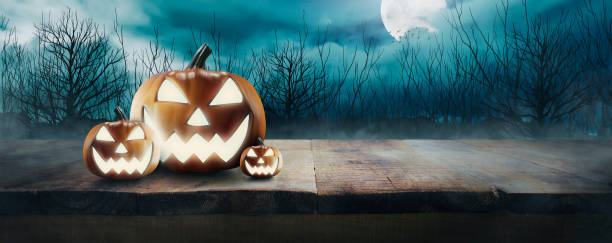 istock Jack O 'Lantern's with glowing eyes on a wooden table on spooky Halloween night under full moon light 1675221272