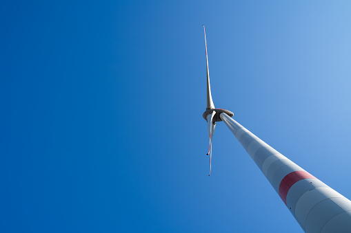 View from bellow of a huge wind turbine in the blue sky with copy space on the side