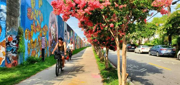 In Atlanta, United States people bike along a sidewalk lined with painted murals in Inman Park by the Beltline trail.