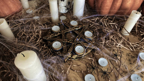 istock An invitation to Halloween. A round gilded altar with a five-pointed star with extinguished candles, a skull, pumpkins and spiders. A witch's altar in a spider's web. 1675285156
