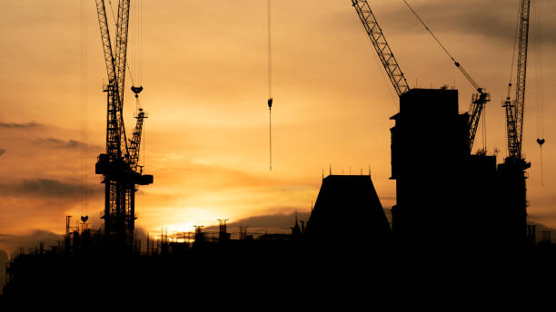 istock Silhouette of Construction site with crane and mechanical equipments. Building Site with Silhouetted Crane in the City. 1675286477