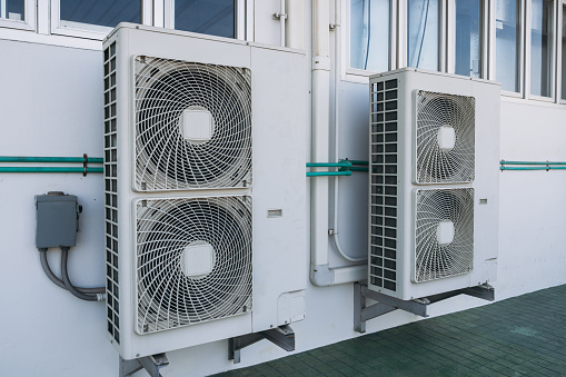 Air conditioner compressor installed on the roof of a building, along with industrial air conditioning units and ventilation systems.