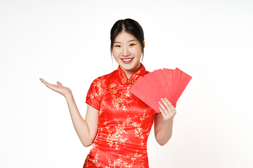 Asian woman wearing traditional cheongsam qipao dress showing something and holding angpao or red packet monetary gift isolated on white background. Happy Chinese new year.