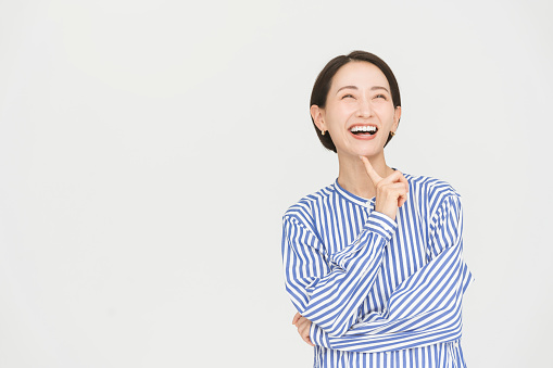 A gesture of a bob-haired Japanese woman wearing a blue striped shirt dress.She smiles in understanding.
