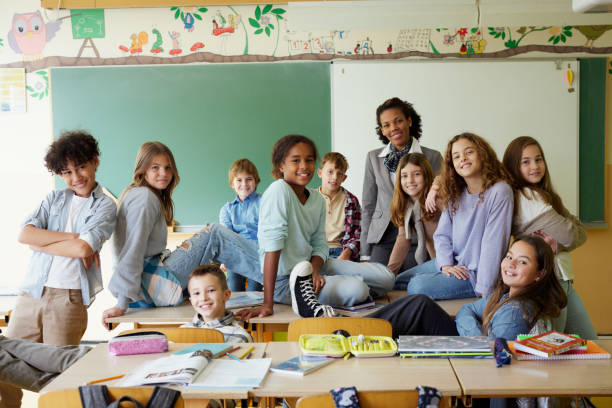 istock Happy elementary students with their female teacher in the classroom. 1675310853
