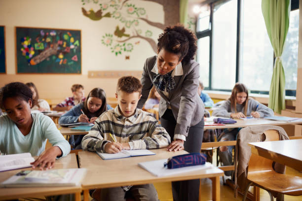 istock Black teacher assisting school kids on a class at elementary school. 1675310905