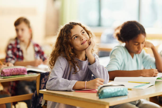 istock Smiling schoolgirl day dreaming on a class at elementary school. 1675317875