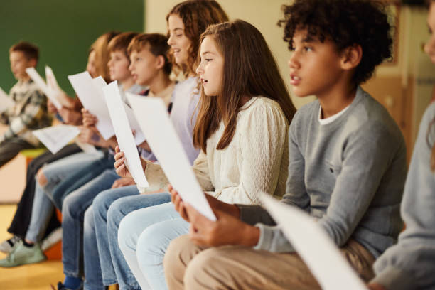 istock School kids practicing with sheet music on a class at school. 1675321618
