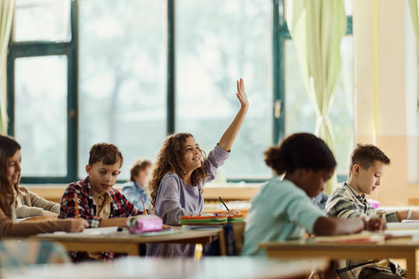 istock Happy schoolgirl raising her hand on a class at elementary school. 1675323216