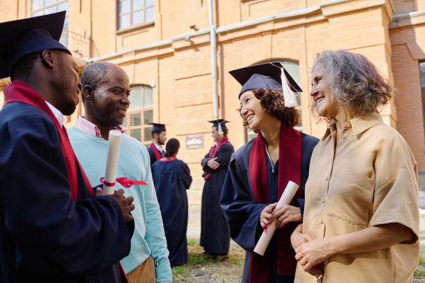 Parents congratulating their children with graduation of university while they standing outdoors