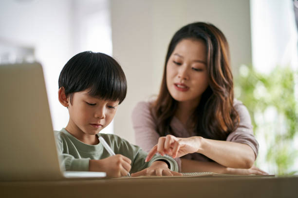 young asian mother helping son with homework stock photo