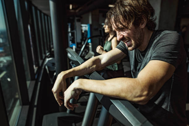 istock Exhausted male athlete taking a break from exercising on a treadmill in a gym. 1675408691