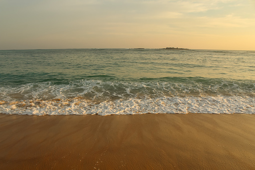 Beach with golden sand and blue ocean water on most popular Unawatuna beach on Sri Lanka, background image with copy space