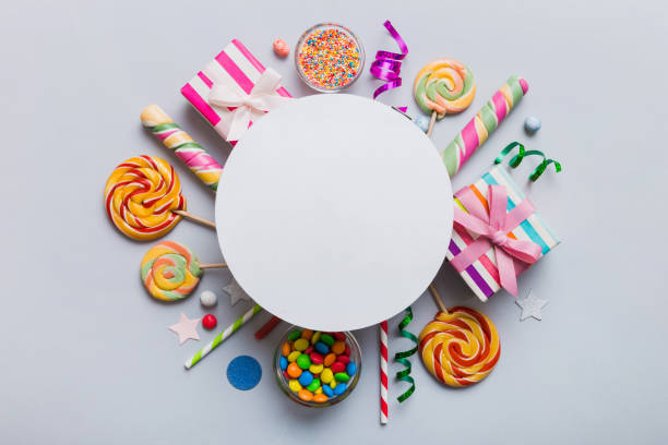 istock Flat lay holiday composition. Paper blank, lollipop, birthday decorations on Colored background. Top view, copy space for text 1675450242