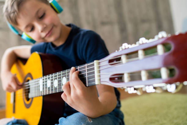istock Close-up of boy playing guitar 1675461541