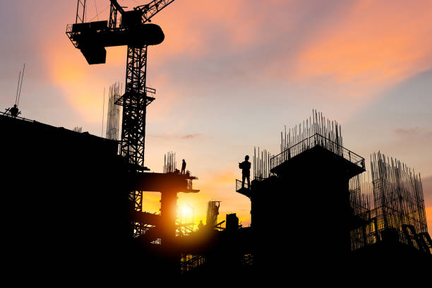 istock Silhouette of Engineer and worker checking project at building site background, construction site at sunset in evening time 1675477628