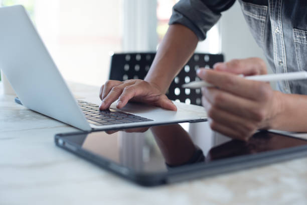istock Close up of business man hand working on laptop computer, surfing the internet and using digital tablet on office table 1675480325