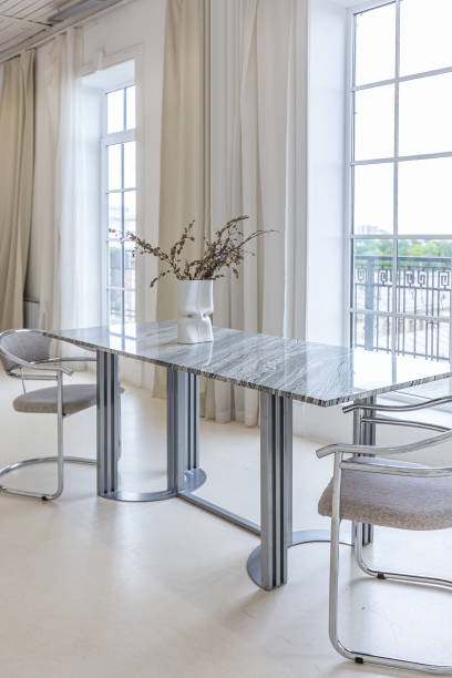 istock marble dining table and two chairs against the backdrop of a panoramic window into the interior of a bright living room in a luxurious Baroque style with white walls decorated with antique stucco 1675496453
