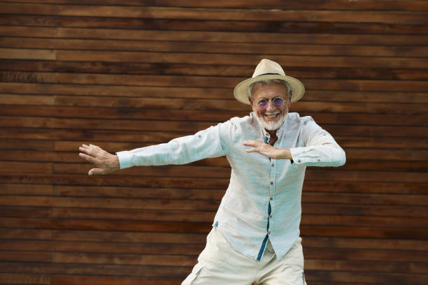 Portrait of happy mature man in a suit having fun while dancing against brown background. Copy space.