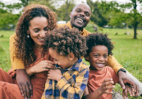 Happy black family, parents and children in a park in summer, smile and relax on grass field for love and fun in nature. Happiness, picnic and portrait of African people outdoor and playing together