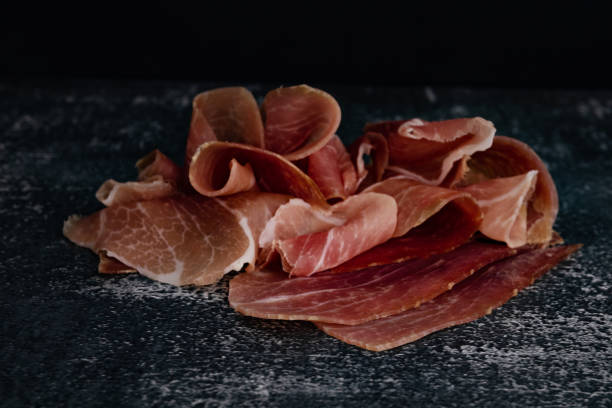 pieces of pork meat on a black background. italian prosciutto on a dark background - stone textured italian culture textured effect imagens e fotografias de stock