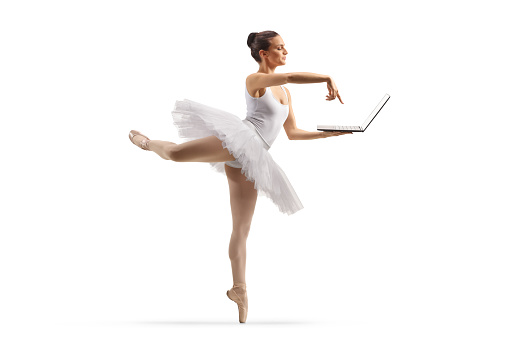 Full length shot of a ballerina dancing and using a laptop computer isolated on white background