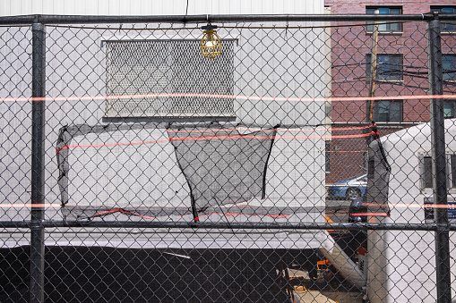 Broadway, Long Island City, Queens, New York, USA - August 19th 2023:  Reinforced mesh wire fence at a scaffold outside a construction site