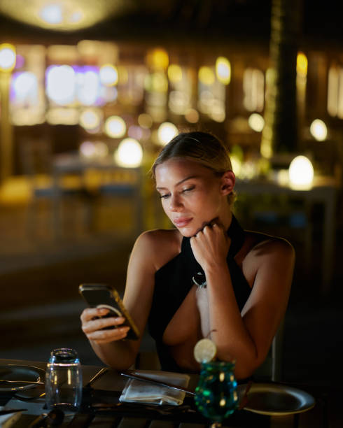 istock Beautiful woman using mobile phone in a restaurant at night. 1675552553