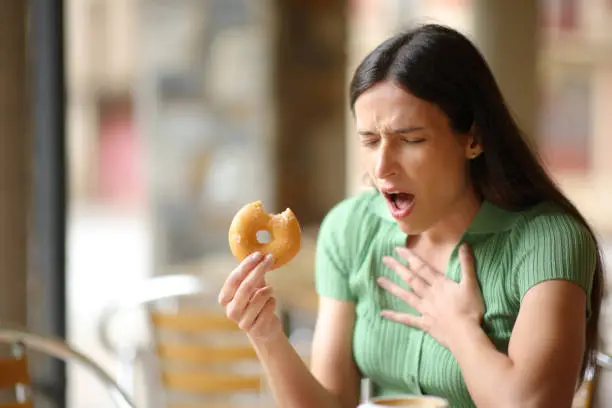 Woman choking eating doughnut in a bar