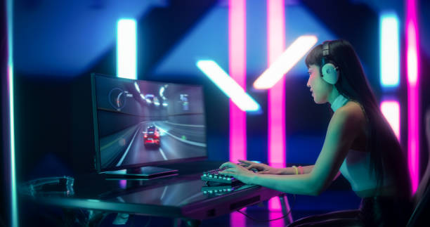 コンピューターでオンラインレーシングゲームをプレイする若い日本の女性ゲーマー。ヘッドフォンで興奮した女性のポートレート、ウェブモータースポーツシミュレーターで多様なプレー�