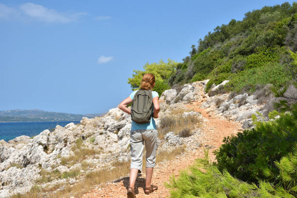 istock Woman with backpack walking on the path near the sea 1675568959